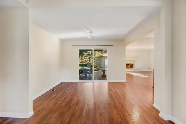 an empty room with wooden floor ceiling fan and windows