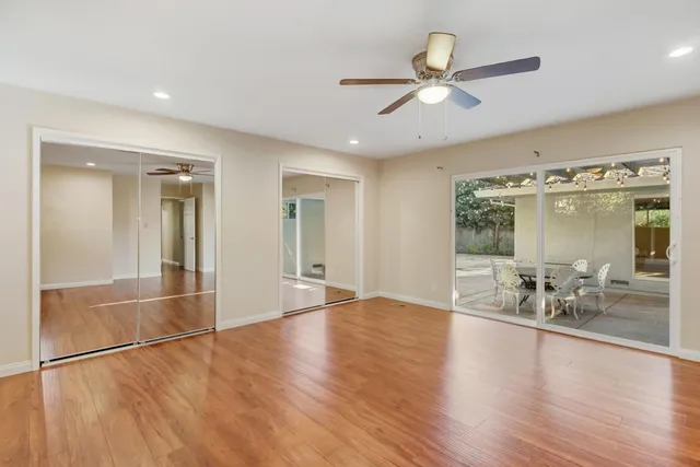 an empty room with wooden floor and windows