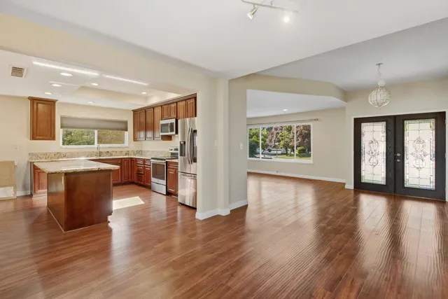 a kitchen with stainless steel appliances granite countertop a refrigerator a sink dishwasher a stove with wooden floors and cabinets