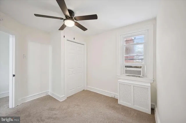 an empty room with windows and fan