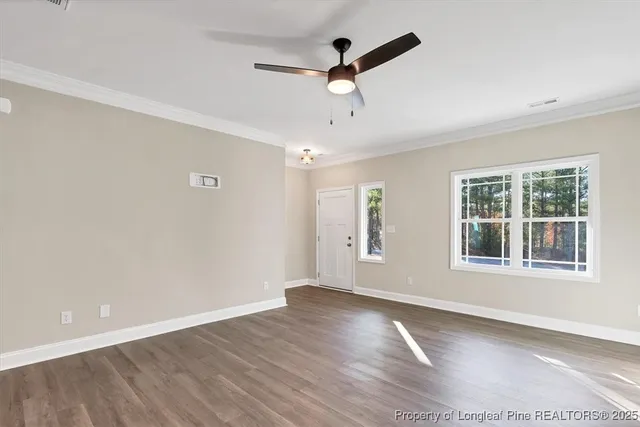 an empty room with wooden floor ceiling fan and windows