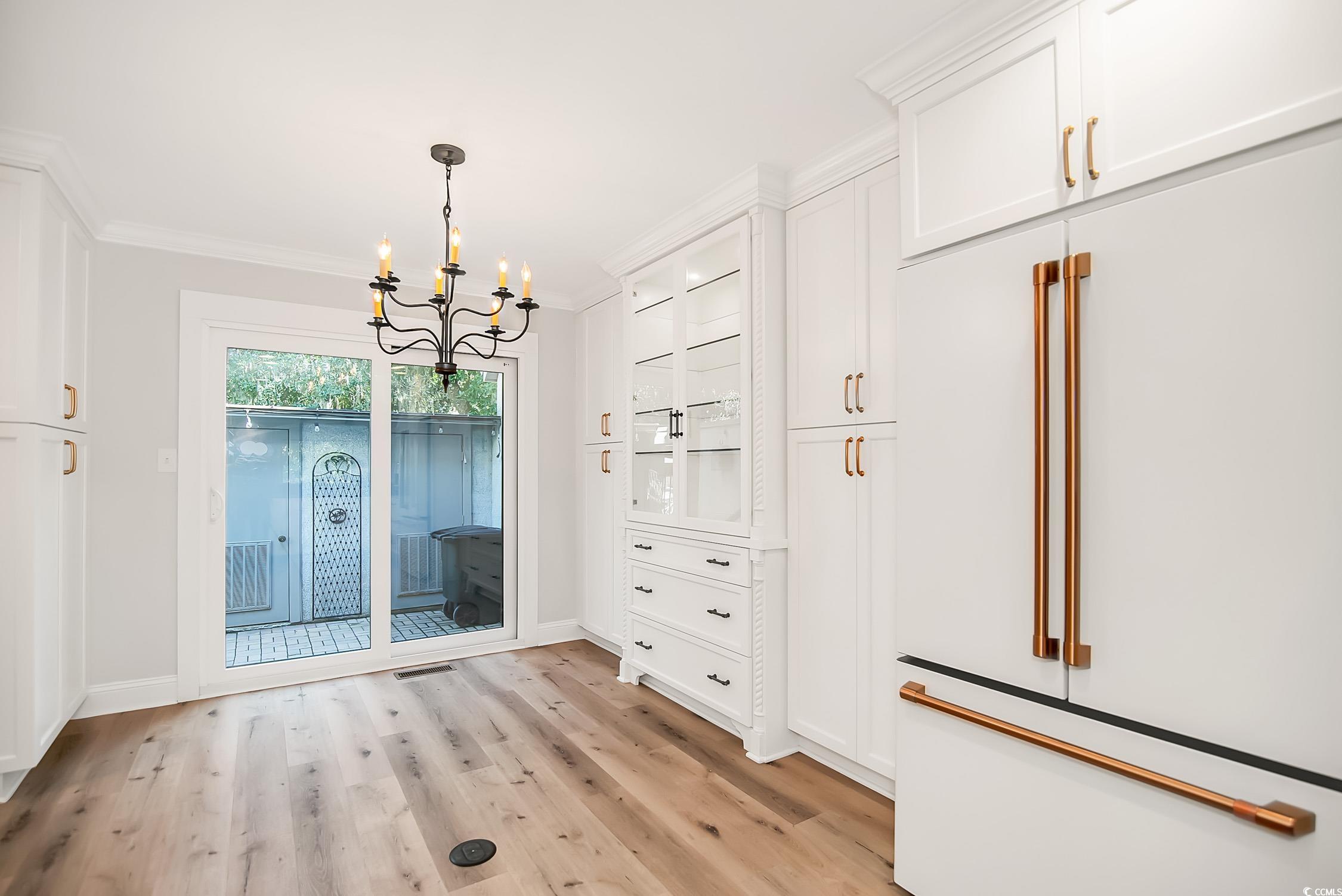 63 Battery White Court, Unit 2C Georgetown, SC 29440 - Photo 11 of 38 Unfurnished dining area featuring light wood finished floors, a chandelier, and ornamental molding