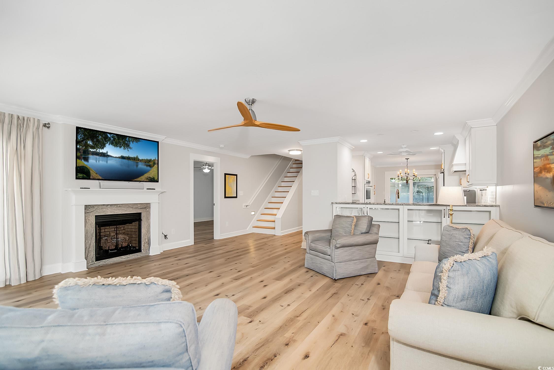 63 Battery White Court, Unit 2C Georgetown, SC 29440 - Photo 13 of 38 Living area featuring crown molding, a chandelier, light wood finished floors, a fireplace, and recessed lighting