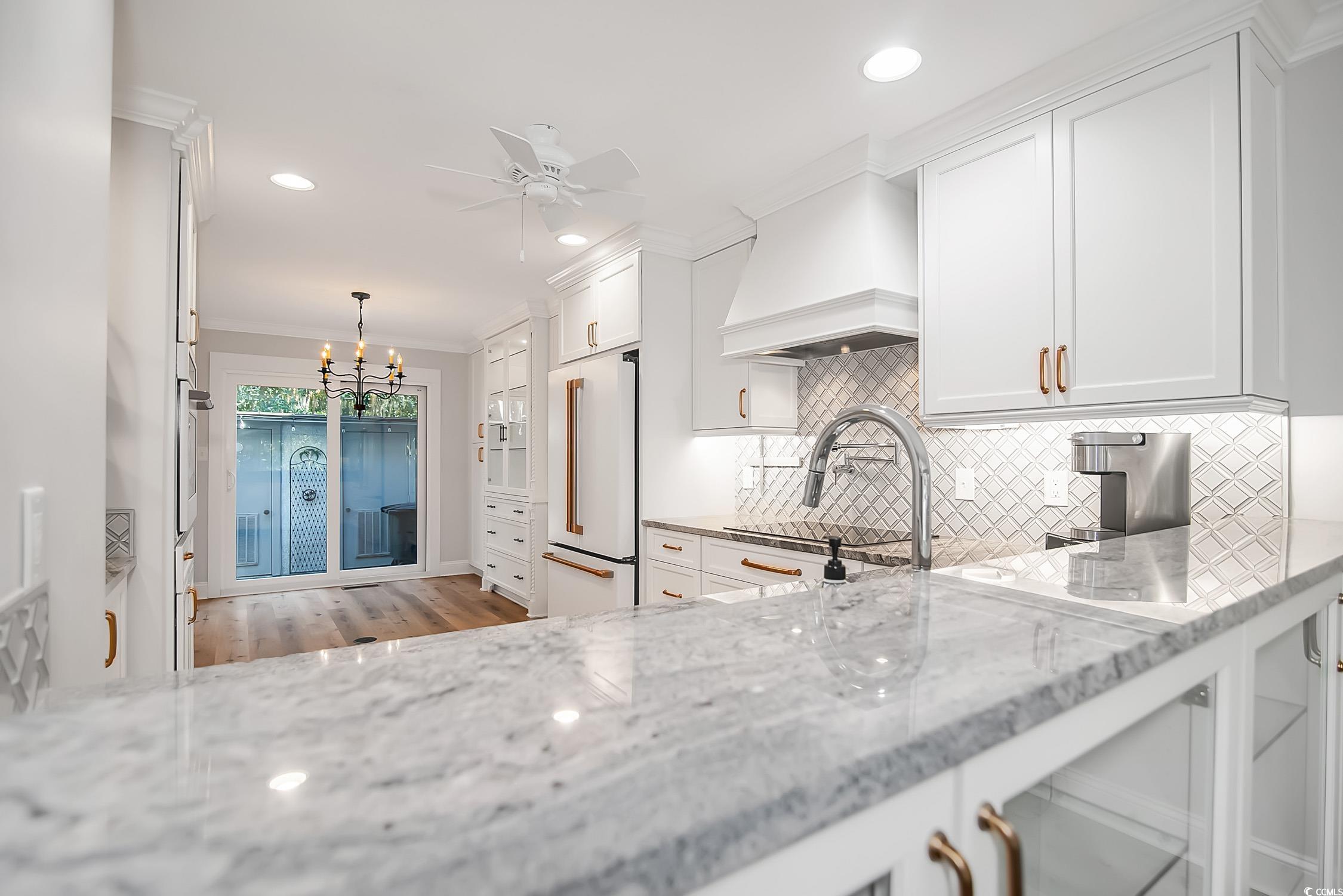 63 Battery White Court, Unit 2C Georgetown, SC 29440 - Photo 3 of 38 Kitchen with crown molding, backsplash, white cabinetry, light stone counters, and high end white fridge