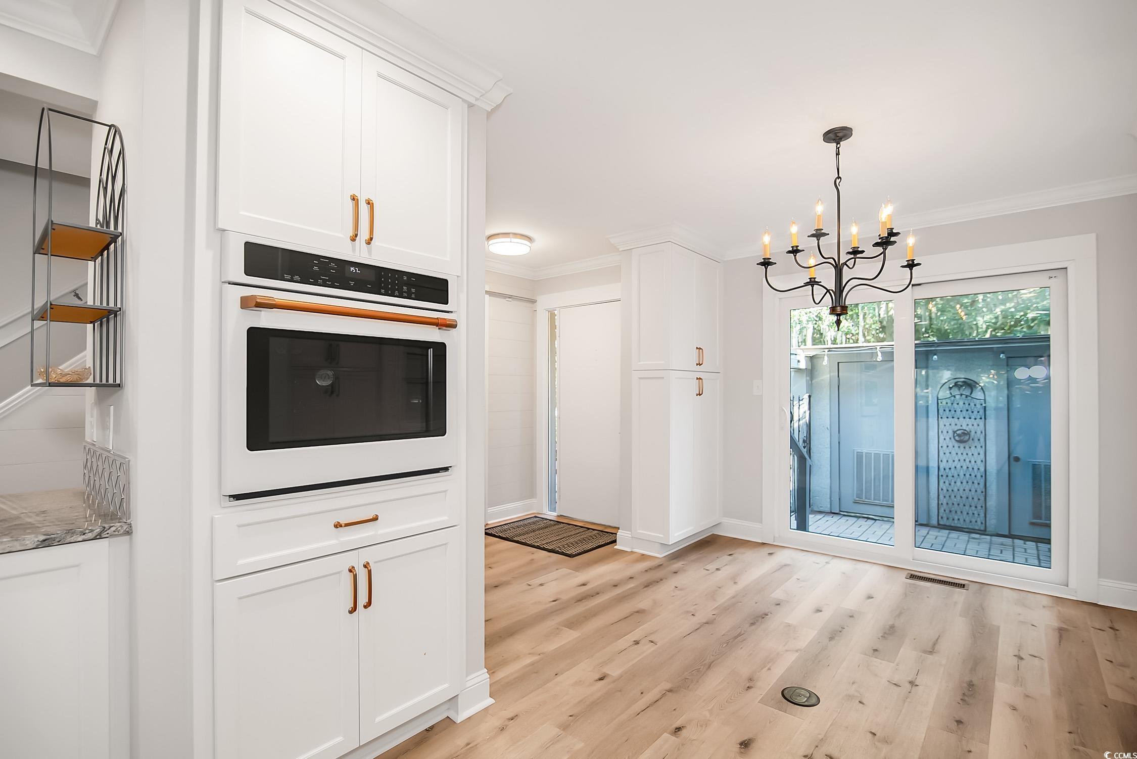 63 Battery White Court, Unit 2C Georgetown, SC 29440 - Photo 6 of 38 Kitchen with ornamental molding, oven, white cabinetry, light wood-style flooring, and pendant lighting