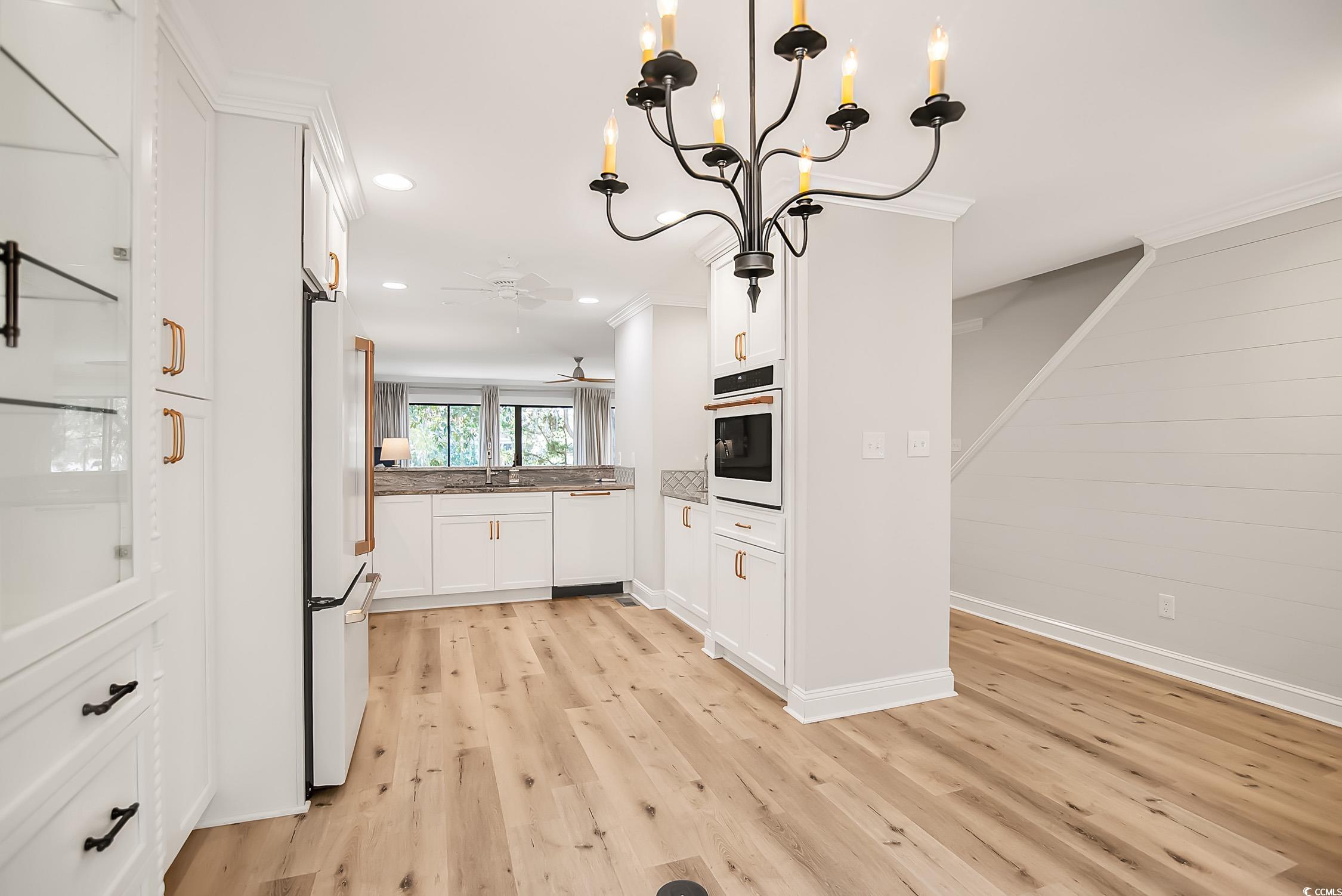 63 Battery White Court, Unit 2C Georgetown, SC 29440 - Photo 9 of 38 Kitchen featuring white cabinetry, a chandelier, light wood finished floors, crown molding, and white appliances