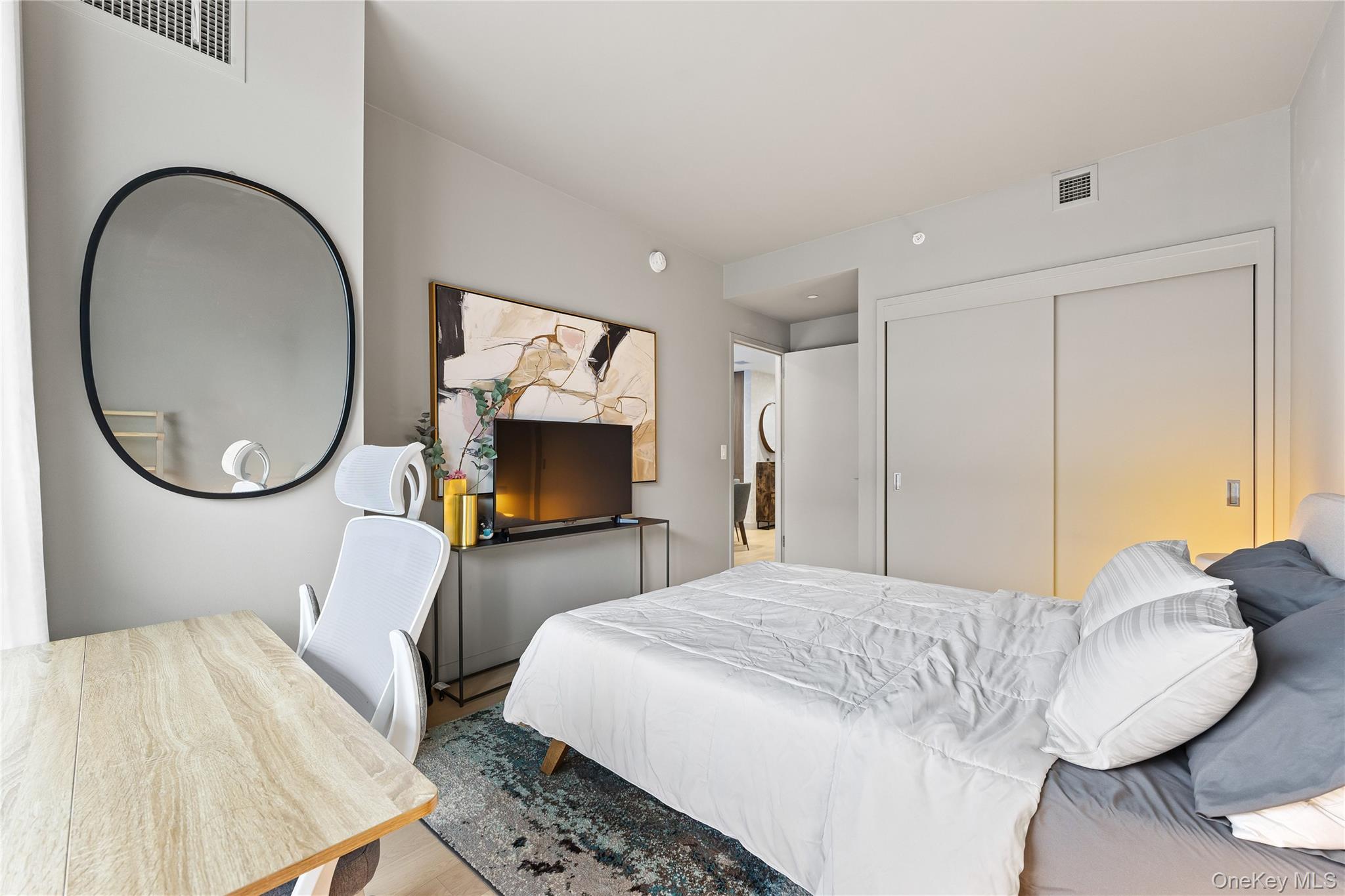 131-01 40 Road, Unit PH3F Queens, NY 11354 - Photo 14 of 30 a bedroom with a bed a mirror on dresser and a large window