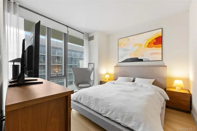 a bedroom with a bed and a flat tv screen on dresser
