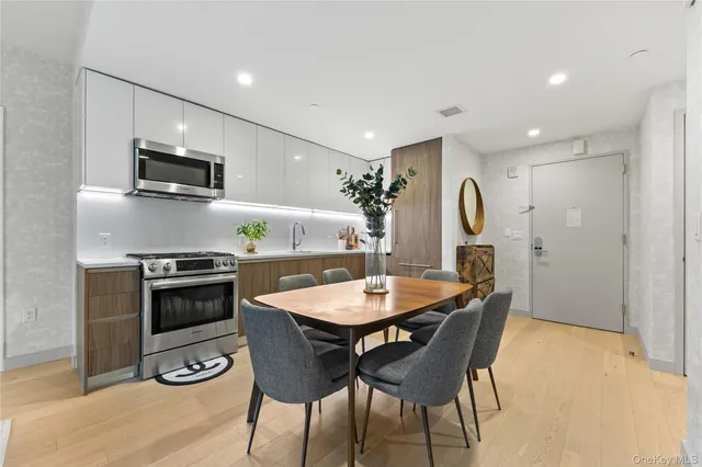 a kitchen with stainless steel appliances granite countertop a stove a sink a microwave a dining table and chairs