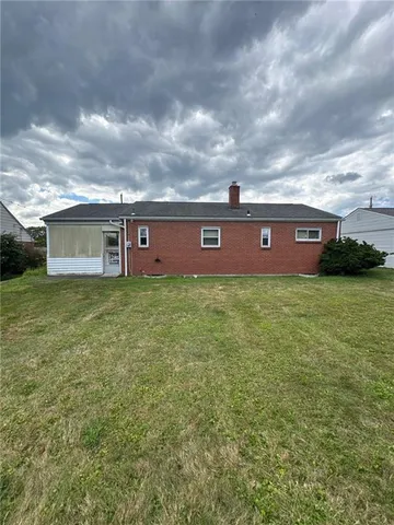 a view of a house next to a big yard with plants and large trees
