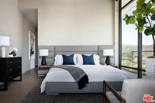 a bedroom with a bed lamp and a large window with outer view