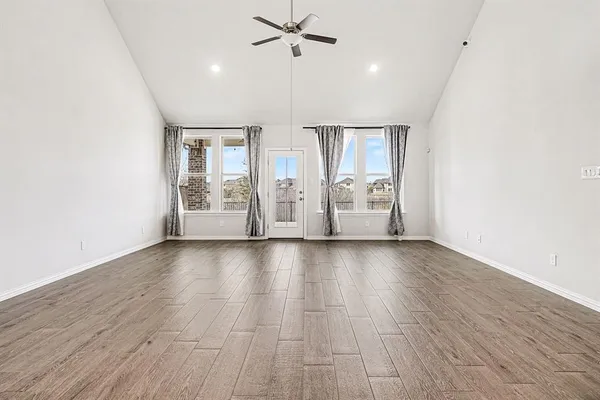 a view of an empty room with a window and wooden floor
