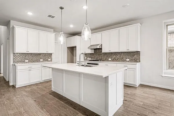 a kitchen with stainless steel appliances white cabinets a sink a stove a refrigerator and island with wooden floor