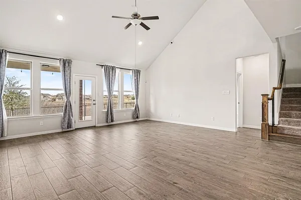 a view of an empty room with a window and wooden floor