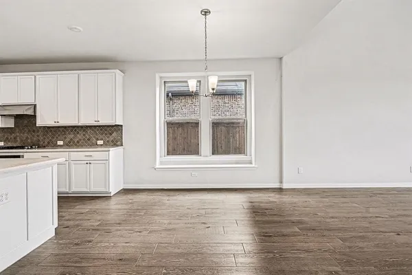 a view of kitchen with granite countertop window and white cabinets