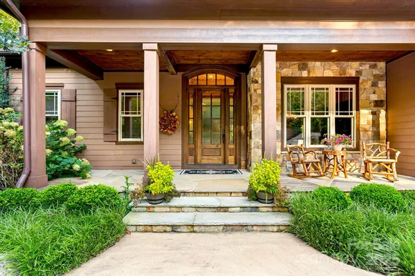 a front view of a house with potted plants and a fountain