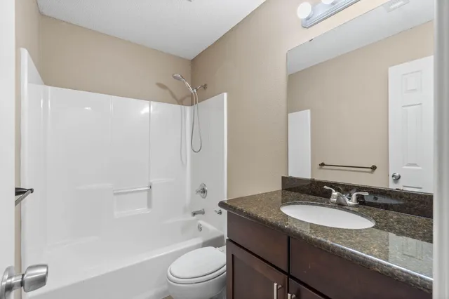 a bathroom with a granite countertop sink toilet and shower