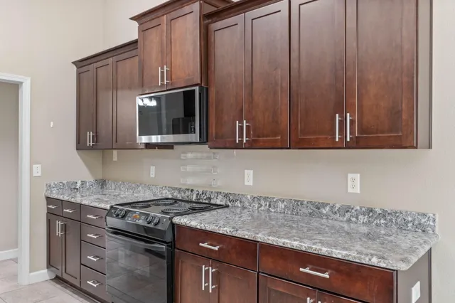 a kitchen with granite countertop a sink cabinets and stainless steel appliances