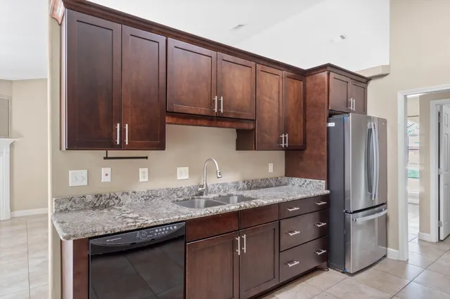 a kitchen with stainless steel appliances granite countertop wooden cabinets a refrigerator and a sink