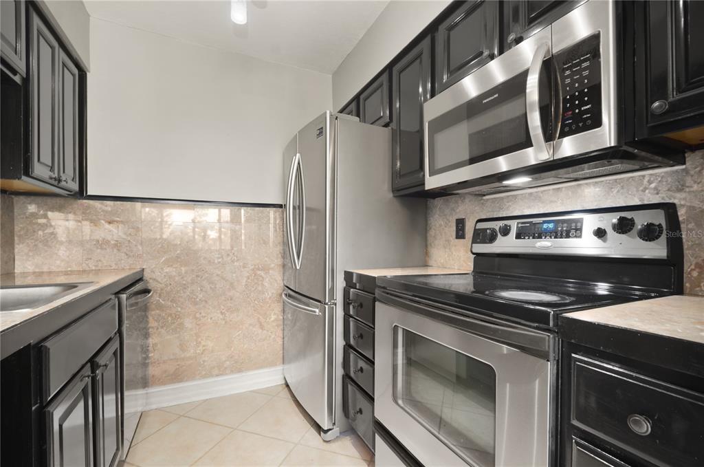 5929 Windhover Drive, Unit A02 Orlando, FL 32819 - Photo 5 of 17 a kitchen with stainless steel appliances granite countertop a stove microwave and refrigerator