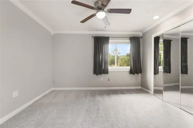 an empty room with chandelier fan and windows