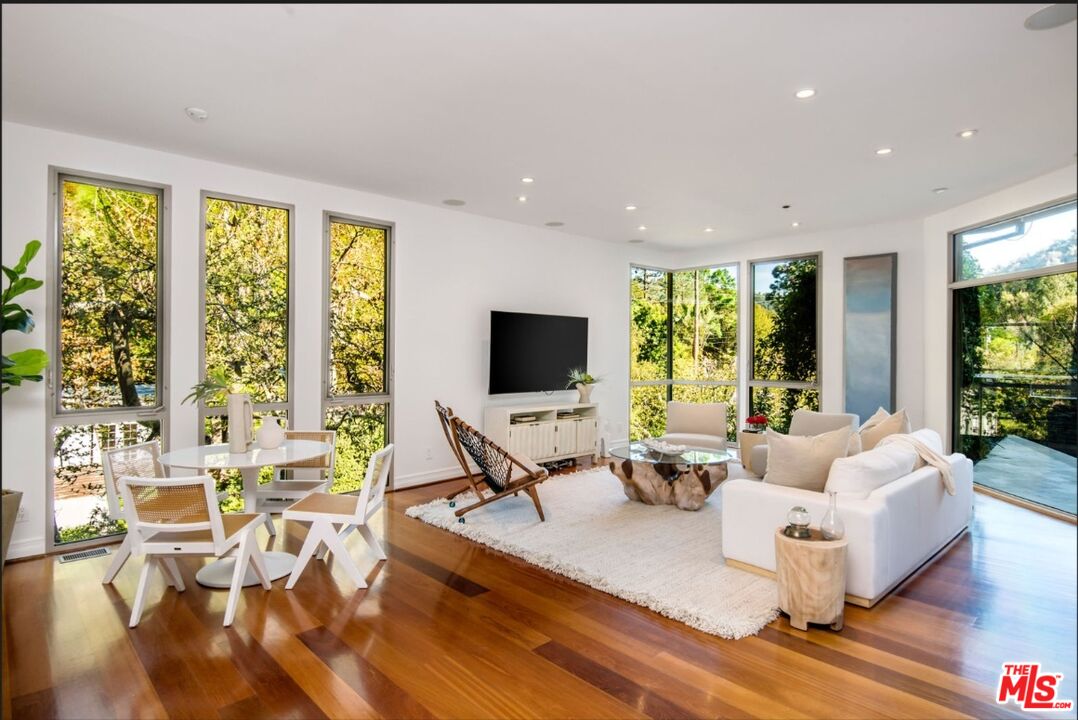 3685 Mandeville Canyon Road Los Angeles, CA 90049 - Photo 4 of 24 a living room with fireplace furniture and floor to ceiling windows