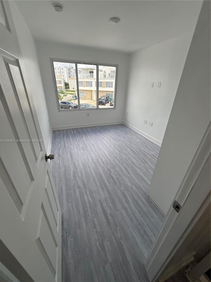 13984 Southwest 259th Street, Unit 13984 Homestead, FL 33032 - Photo 12 of 67 wooden floor in an empty room with a window