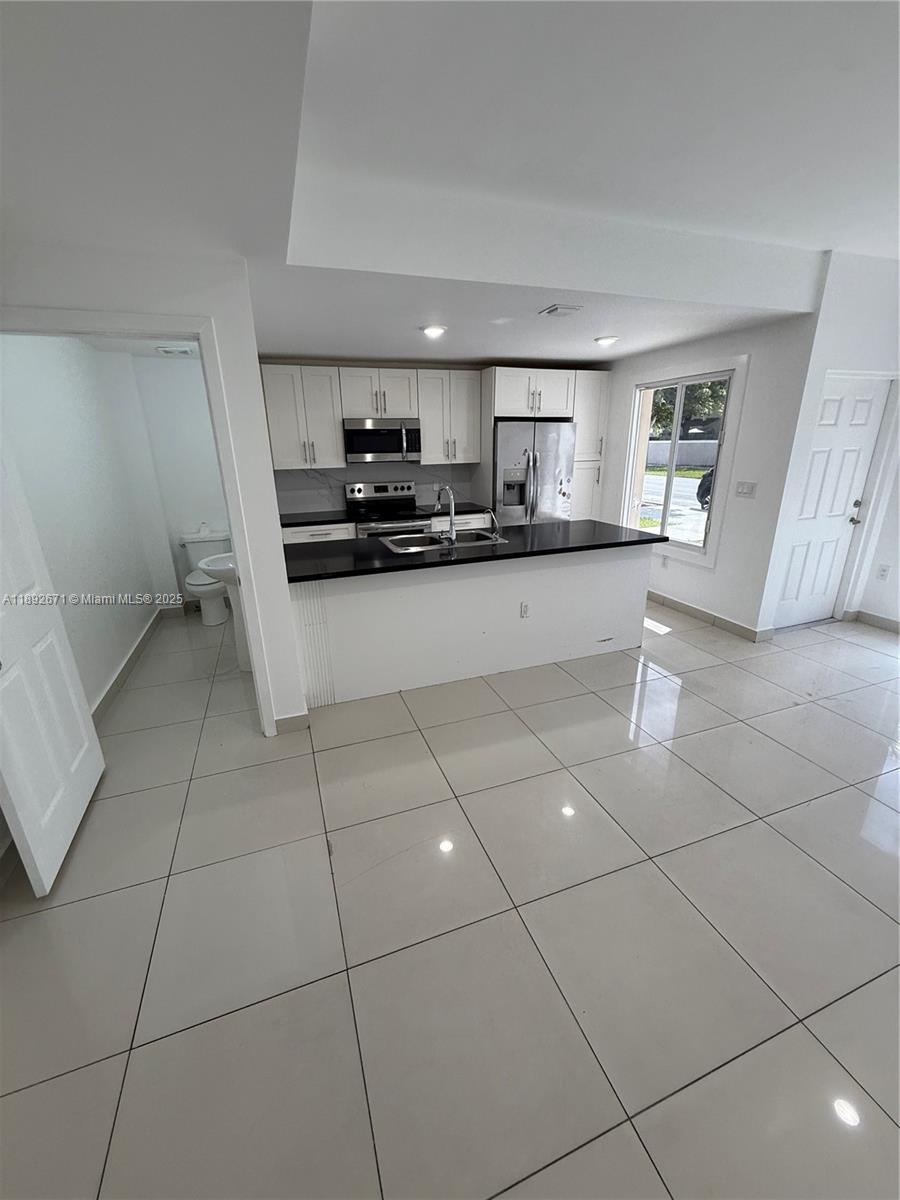 13984 Southwest 259th Street, Unit 13984 Homestead, FL 33032 - Photo 43 of 67 a kitchen with stainless steel appliances a sink a stove a microwave and cabinets