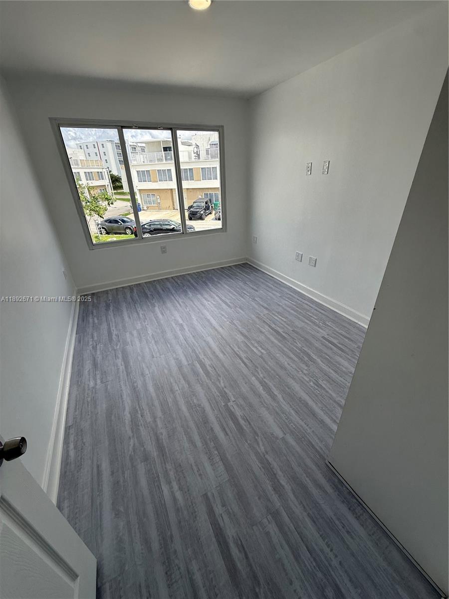 13984 Southwest 259th Street, Unit 13984 Homestead, FL 33032 - Photo 6 of 67 an empty room with wooden floor and windows