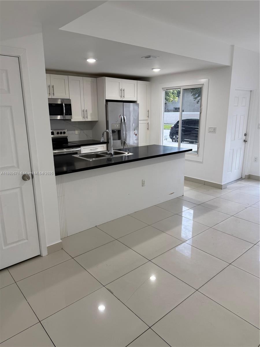13984 Southwest 259th Street, Unit 13984 Homestead, FL 33032 - Photo 8 of 67 a kitchen with stainless steel appliances a sink a stove a microwave a sink a refrigerator and cabinets
