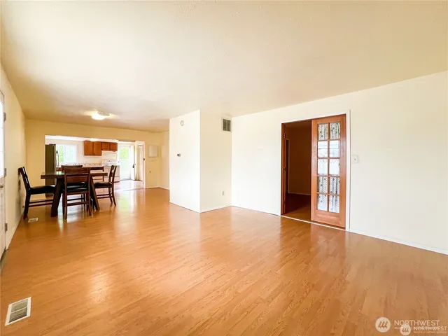 a view of an empty room with kitchen and dining room