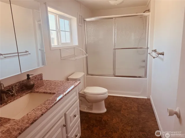 a bathroom with a granite countertop sink toilet and shower