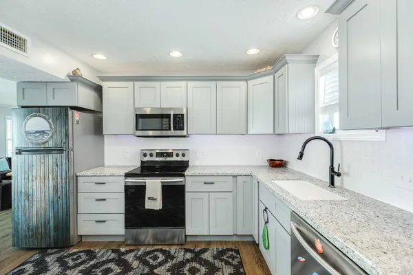 a kitchen with stainless steel appliances granite countertop a stove a sink and a microwave