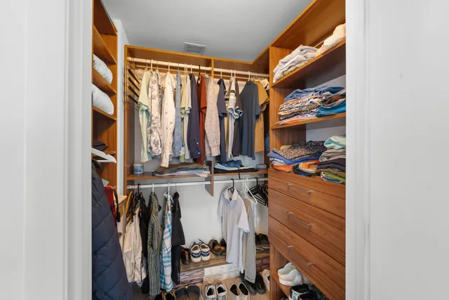 a view of walk in closet with clothes and shoes