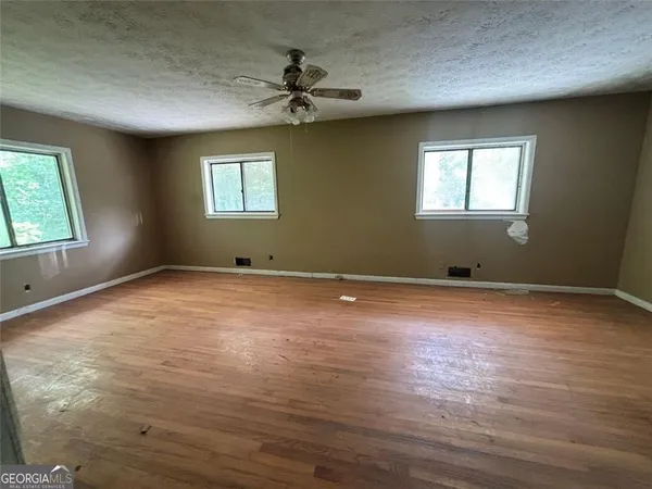 a view of empty room with wooden floor and fan