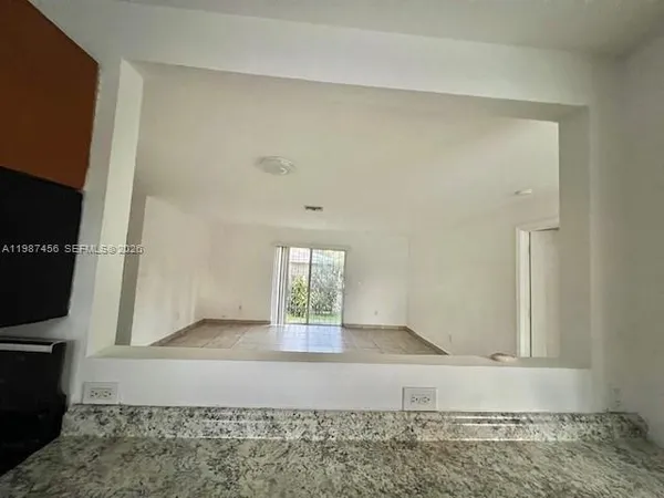 a view of a livingroom with an empty space and a refrigerator