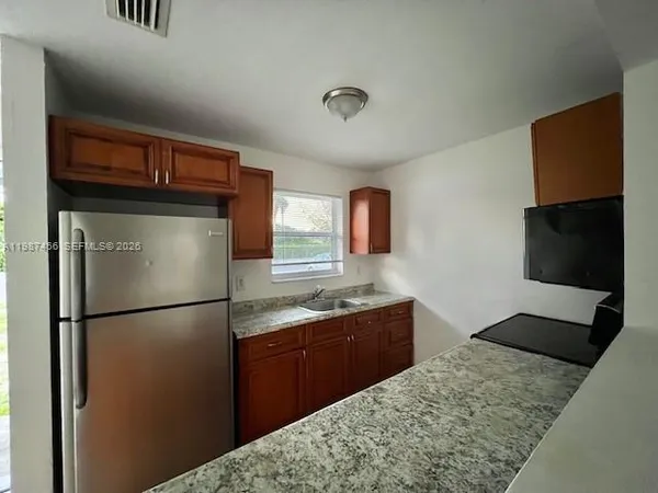 a kitchen with stainless steel appliances granite countertop a refrigerator a stove and a sink