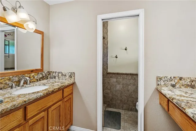 a bathroom with a granite countertop sink a mirror and a shower
