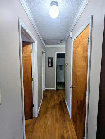 a view of a hallway with wooden floor and a bathroom
