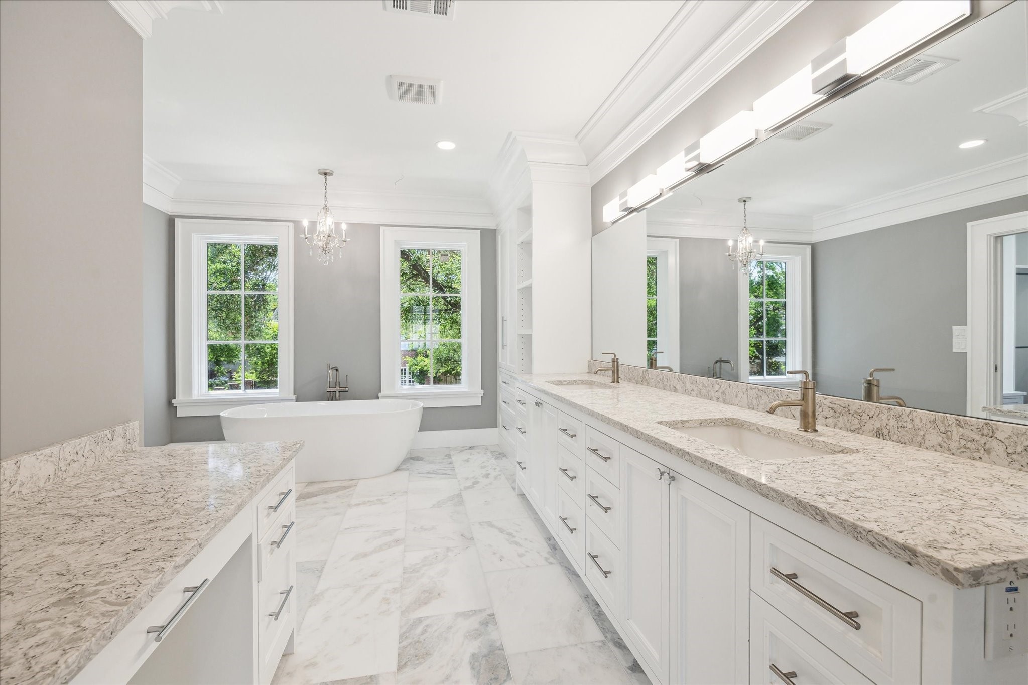 2216 Tangley Street Houston, TX 77005 - Photo 11 of 44 The luxurious primary bathroom features a double vanity with marble countertops, elegant light fixtures, a freestanding bathtub, and large windows providing ample natural light.