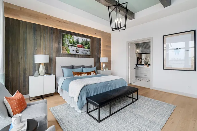 a bedroom with a bed couch chandelier and a window