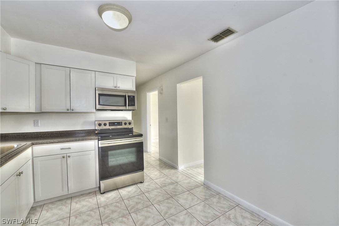 117 Rowland Road Lehigh Acres, FL 33936 - Photo 11 of 26 a kitchen with white cabinets stainless steel appliances and a sink