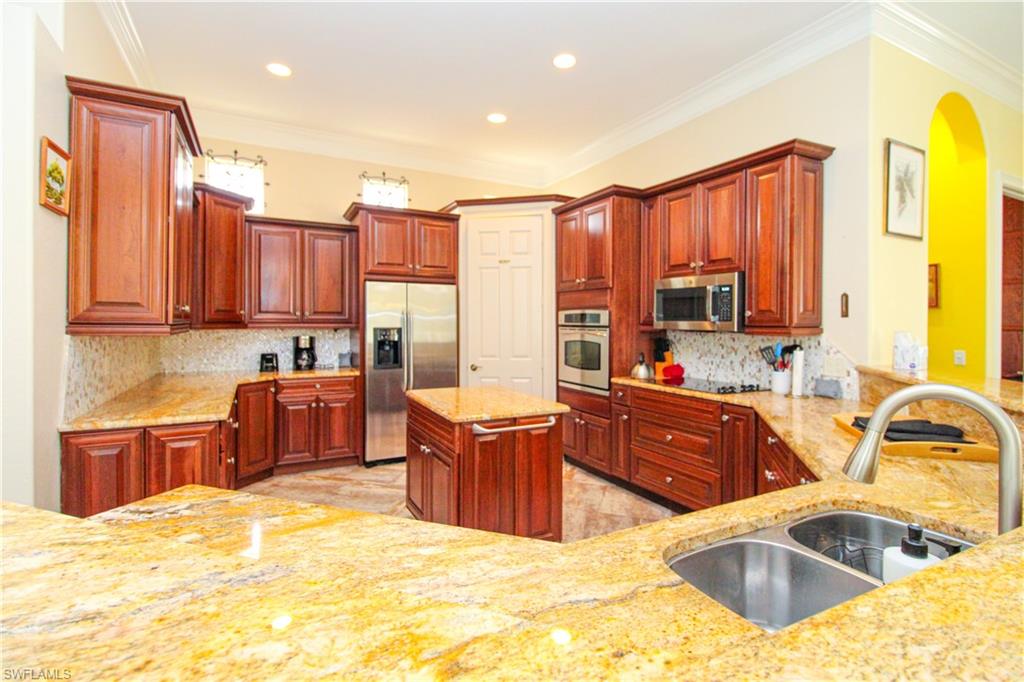 627 Soliel Drive Naples, FL 34110 - Photo 13 of 45 a kitchen with stainless steel appliances granite countertop a sink stove and refrigerator