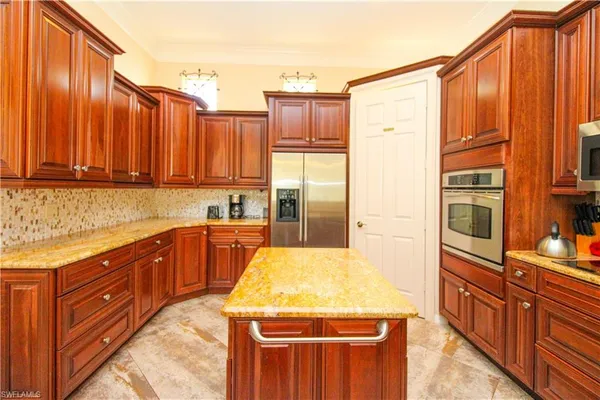 a kitchen with stainless steel appliances granite countertop a refrigerator a sink dishwasher and wooden cabinets with wooden floor