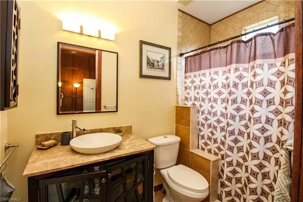 a bathroom with a granite countertop toilet sink and mirror