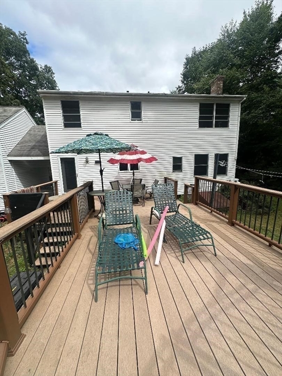 99 Old Poor Farm Road Ware, MA 01082 - Photo 4 of 29 a view of a roof deck with table and chairs a barbeque with wooden floor and fence