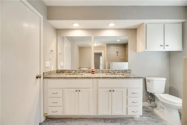 a bathroom with a granite countertop toilet a sink and a mirror