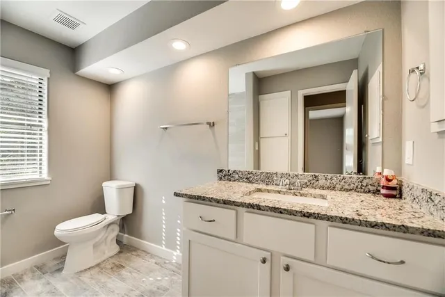 a bathroom with a granite countertop sink toilet and mirror