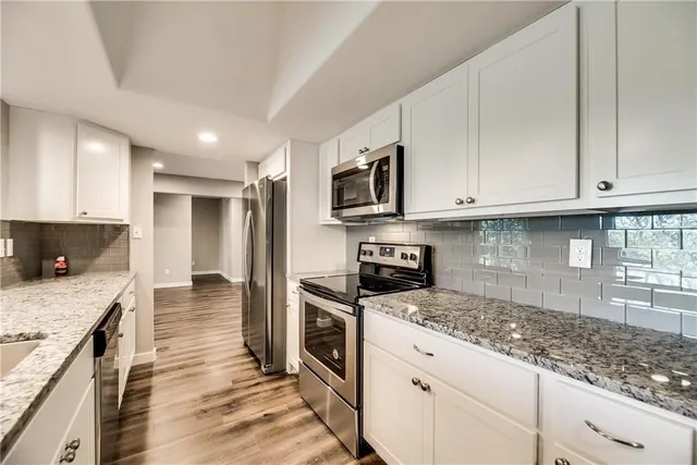 a kitchen with stainless steel appliances granite countertop a stove a sink and a microwave