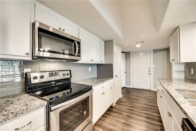 a kitchen with stainless steel appliances granite countertop a stove microwave and cabinets